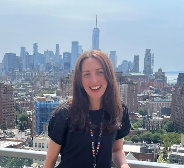 Michaela on a rooftop terrace, smiling, with the Manhattan skyline behind her